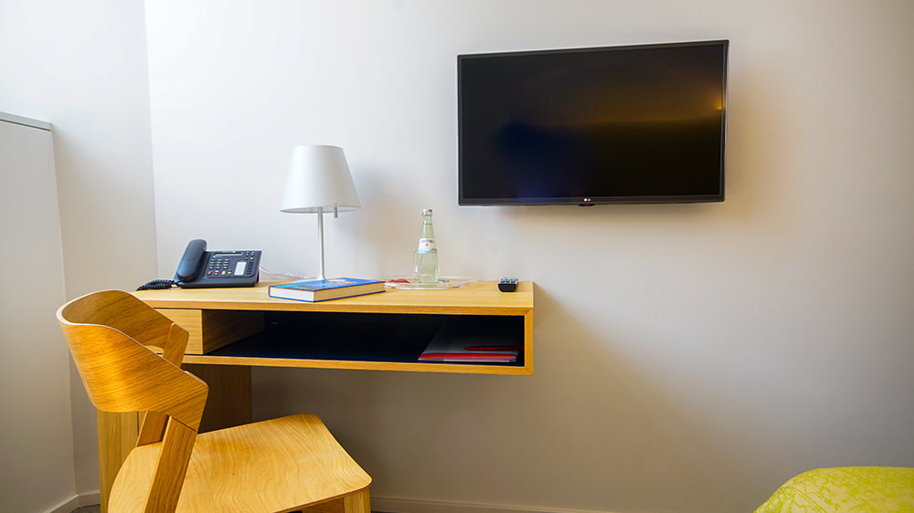 Büroraum im KSI mit Telefon auf Schreibtisch, Stuhl und Monitor an der Wand