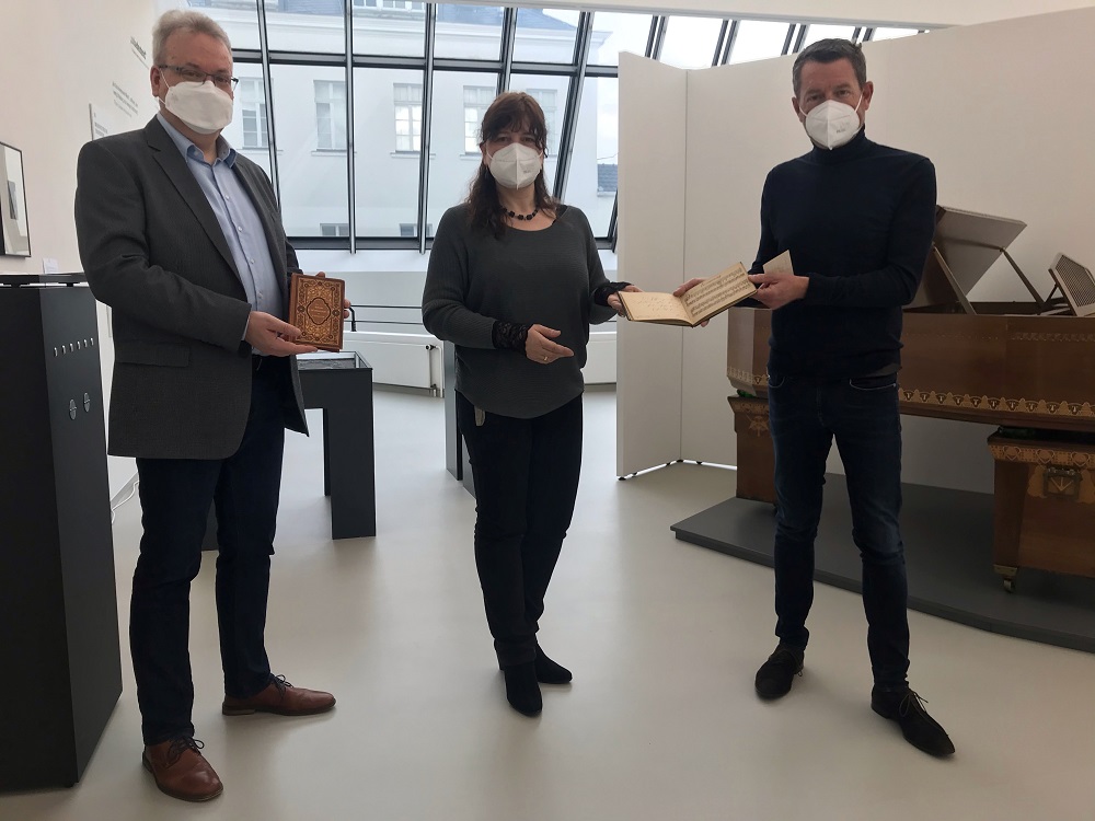 Kai Diekmann übergibt das Poesiealbum an Museumsleiterin Dr. Gundula Caspary. Dr. Christian Ubber hält den Gedichtband des Humperdinckvaters Gustav in Händen.