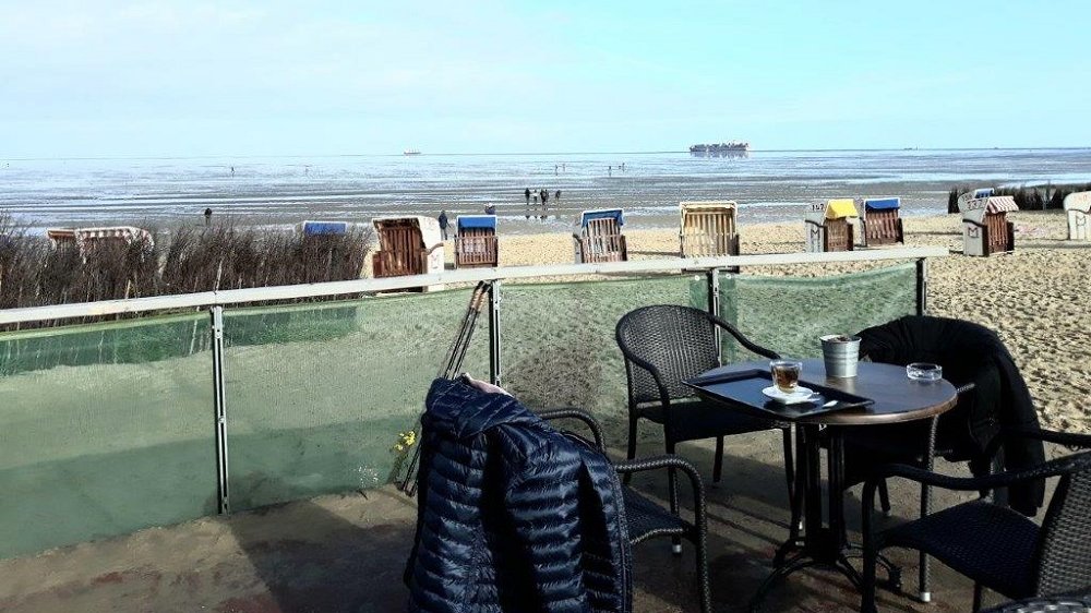 Blick von einer Terrasse über Strandkörbe aufs Wattenmeer