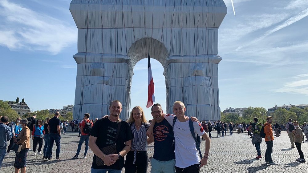Vier Personen vor dem verhüllten Arc de Triomphe