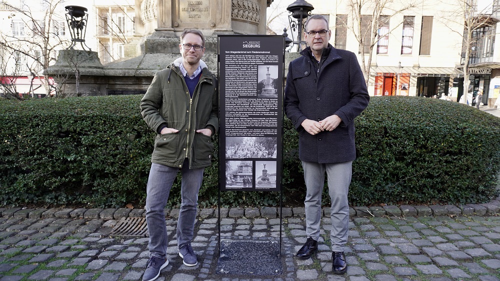 Stadtarchivar Jan Gerull und Bürgermeister Stefan Rosemann vor einer Info-Stele
