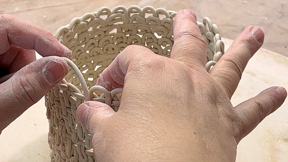 Hände von Keramikerin Petra Bittl, die dünne Tonschnüre zu einer Schale zusammenlegen.