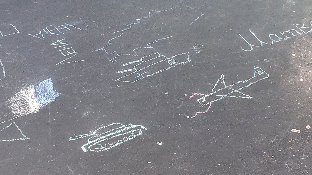 Mit Kreide auf die Straße gemalte Panzer und Flugzeuge.