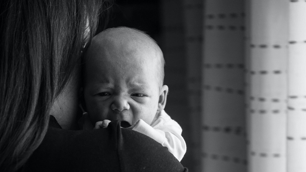 Weinendes Baby an der Schulter seiner Mutter