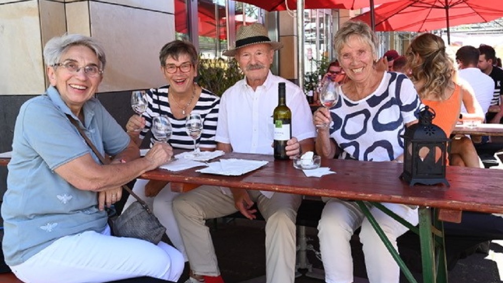 Drei Frauen und ein Mann beim Weintrinken.